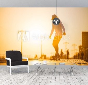 Picture of Silhouette of young boy riding longboard on the boardwalk summer time sunset